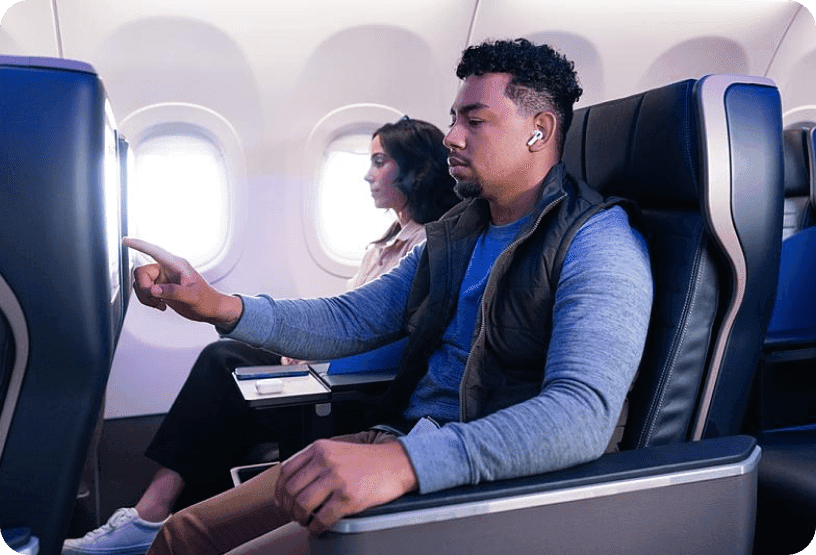 A traveler using the touchscreen on his inflight entertainment screen on a plane.