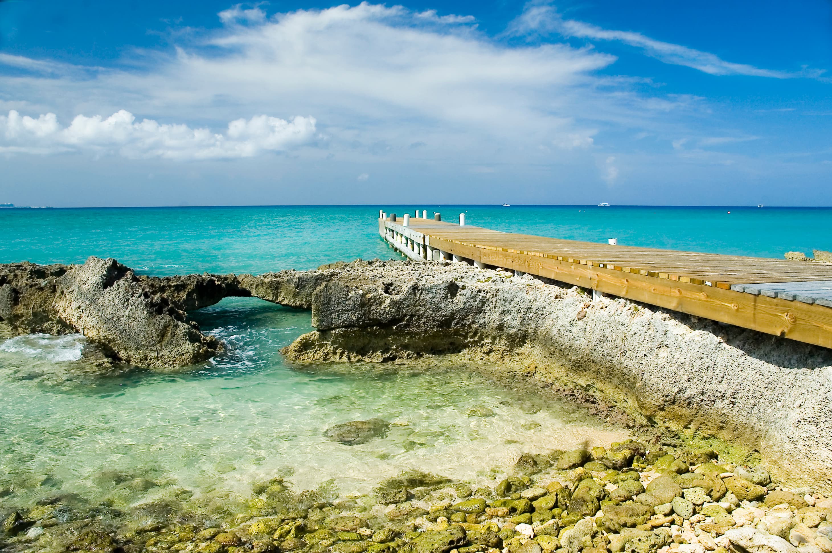 Tropical beach with turquoise waters and a wooden dock extending into the ocean